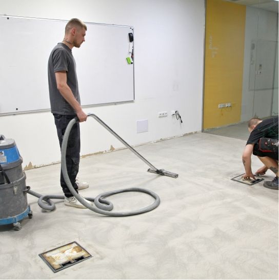 Muž vysává vysavačem podlahu