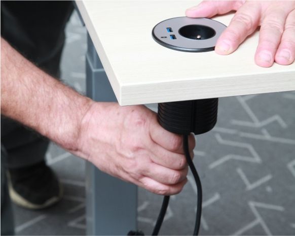 Ruka připevňující kabely do stolu